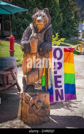 2021 06 05 9999 Crested Butte CO Stati Uniti d'America - Orseto con tazza di caffè in legno intagliato e bandiera arcobaleno segno aperto all'esterno caffè all'aperto in turista Foto Stock