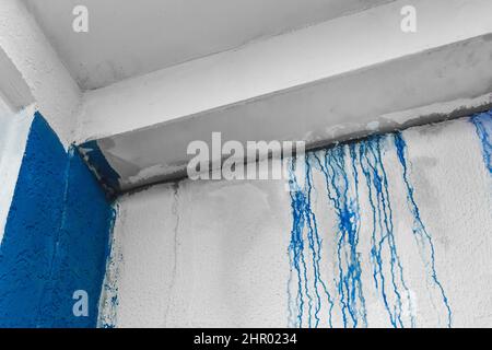 Striature di liquido versato blu vernice giù il intonaco bianco parete astratto disegno sfondo sporco. Foto Stock