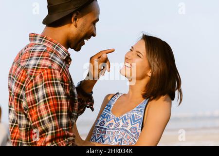 Giovane coppia multirazziale sorridente e abbracciante all'aperto Foto Stock