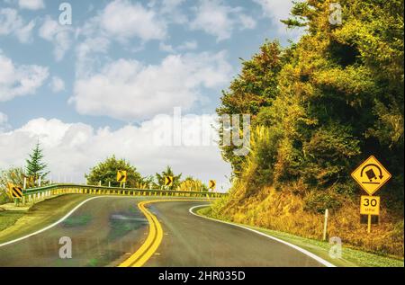 Strada di montagna curva con guardrail e segno di camion ribaltamento Foto Stock
