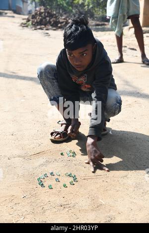 Ragazzo tribale che gioca marmi a Pearson Pally. Il borgo tribale di Santali a Visva-Bharati. Santiniketan, Bolpur, Birbhum, Bengala Occidentale, India. Foto Stock