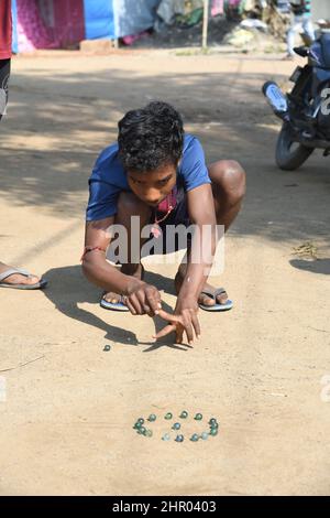 Ragazzo tribale che gioca marmi a Pearson Pally. Il borgo tribale di Santali a Visva-Bharati. Santiniketan, Bolpur, Birbhum, Bengala Occidentale, India. Foto Stock