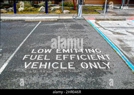 Veicolo a bassa emissione di carburante solo parcheggio con stazione di ricarica elettrica sulla superficie del piano nero aziendale Foto Stock