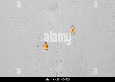 Un chiodo di riferimento è un elemento di costruzione di fissaggio di ritegno in una parete di cemento bianca. Riparazione dell'angolo del giunto angolare dell'industria della costruzione di calcestruzzo str Foto Stock