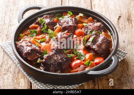 Spagna meridionale cibo Rabo de Toro Oxtail Stew con vino rosso closeup su una pentola sul tavolo di legno. Orizzontale Foto Stock