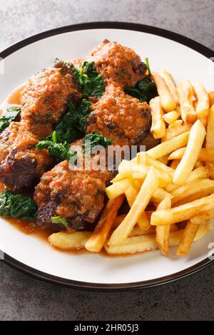 Spanish Bull Tail Stew Rabo De Toro servito con il primo piano di frittura francese nel piatto sul tavolo. Verticale Foto Stock