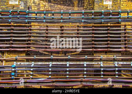 File di fili e tubi su rack fissati a grungy muro di mattoni in ferrovia sotterranea Foto Stock