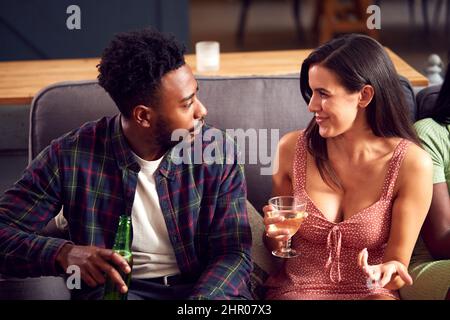 Giovane coppia seduta sul divano a casa parlare e godersi un drink insieme Foto Stock