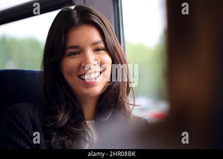 Due donne in viaggio per lavorare in treno che parlano insieme in carrozza Foto Stock