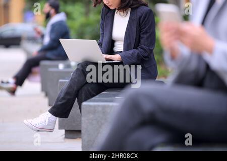 Primo piano di una donna in attività all'aperto che lavora su un notebook durante una pausa dall'ufficio Foto Stock
