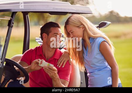 Coppia seduta in Buggy giocando Round on Golf insieme Foto Stock