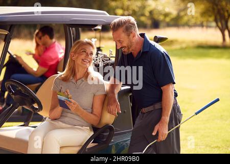 Coppie mature e midrate di adulti in buggy giocando Round on Golf Together Foto Stock