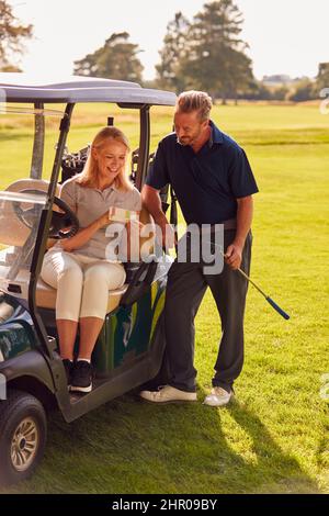 Coppia matura seduta in Buggy giocando Round on Golf e controllando la scheda punteggio insieme Foto Stock