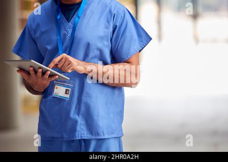 Primo piano del lavoratore medico maschile in scrub con tablet digitale in ospedale Foto Stock