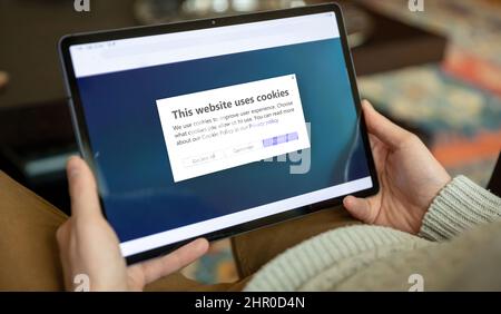 Messaggio informativo sulla politica dei cookie, gestione dei cookie. Uomo che detiene un tablet, sito web chiedere l'autorizzazione dell'utente per l'uso dei dati personali. Foto Stock