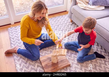 Madre e Figlio a casa gioco Stacking gioco blocchi di legno che Collapse Foto Stock