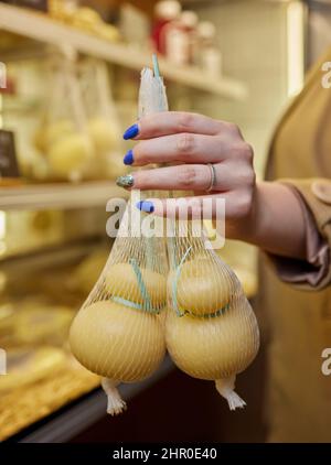 Delizioso Caciocavallo fresco e Scamorza formaggio appeso. Formaggi italiani da vicino. I formaggi sono fatti a mano. La produzione di formaggio Foto Stock