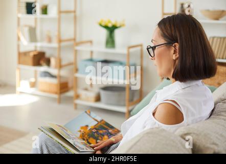 La donna guarda il suo album fotografico di famiglia e ricorda i momenti meravigliosi della sua vita. Foto Stock