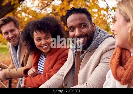 Gruppo di amici all'aperto indossando cappotti e sciarpe in autunno Park Foto Stock
