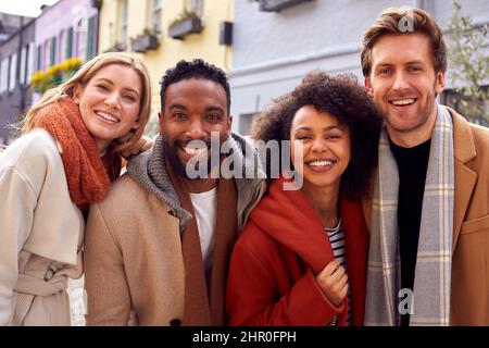 Ritratto all'aperto del gruppo di amici che indossa cappotti e sciarpe in autunno o in autunno Foto Stock