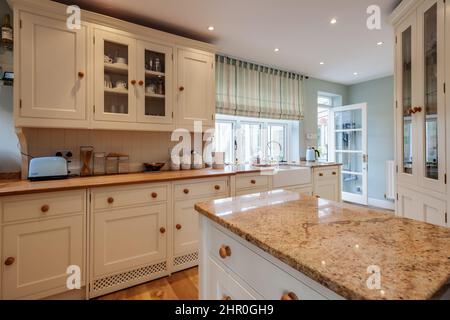 Cavendish, Suffolk - Jan 19 2019: Cucina con armadi a muro, piano in marmo e mobili vetrati Foto Stock