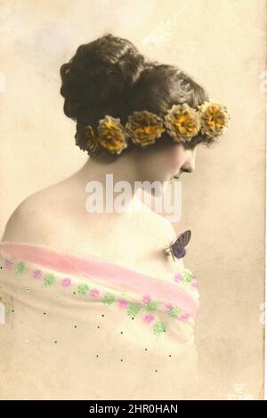 Una bella ragazza di profilo con una farfalla sul collo e una corona floreale sulla testa. Foto Stock