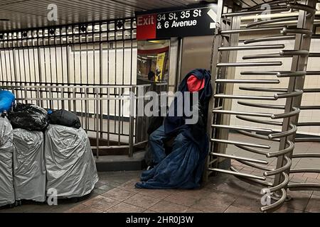 Uomo senza tetto che dorme accanto a una serie di effetti personali alla stazione della metropolitana di 34th Street a Broadway in Manhattan, NYC. Foto Stock