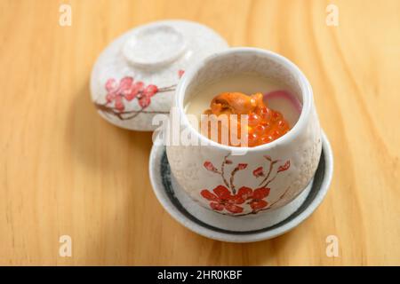 Cucina giapponese uni Chawanmushi in ciotola di tè isolato su sfondo di legno vista dall'alto Foto Stock