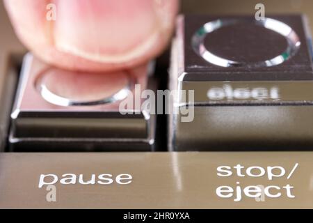 Il dito ha premuto un pulsante di pausa di una macro di registratore di nastri vintage Foto Stock