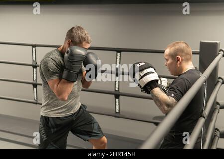 RUSSIA, MOSCA - FEB 14, 2022: Boxe palestra di allenamento donna colpire, per fitness boxer per l'esercizio e combattente di potenza, background competitivo. Abbigliamento sportivo Foto Stock