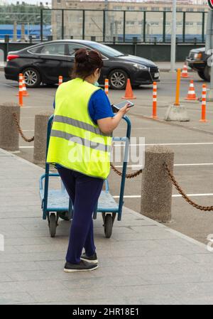 Personale di servizio della stazione ferroviaria con un tram per le cose in attesa di passeggeri, San Pietroburgo, Ladozhsky stazione ferroviaria. Foto Stock