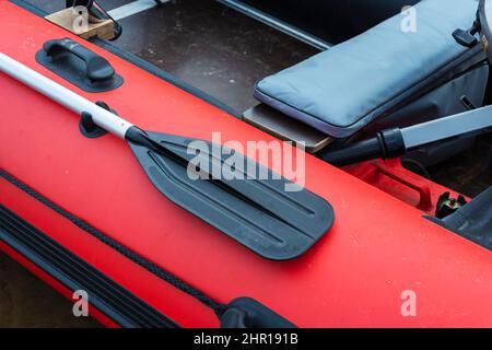 Pagaia a bordo di una barca gonfiabile di gomma, barca gonfiabile rossa con una pagaia, turismo, stile di vita attivo, pesca. Foto Stock