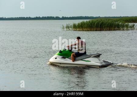 Un giovane cavalca una moto d'acqua sul lago, un uomo cavalca una moto d'acqua, stile di vita attivo, estate, acqua, calore, vacanza. Foto Stock