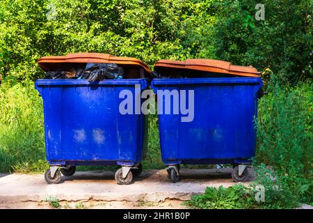 bidoni di spazzatura di strada, spazzatura traboccante da grandi bidoni di spazzatura su ruote per spazzatura, riciclaggio e rifiuti di giardino. Foto Stock