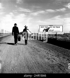 Dorothea Lange - sulla strada per Los Angeles - due uomini sulla strada passano il cartellone ironico che esalta le virtù del viaggio in treno, come se - Marzo, 1937. Foto Stock