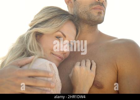 Sicuro tra le braccia. Ritratto di testa e spalle di una giovane donna attraente che abbraccia il marito in una giornata di sole. Foto Stock