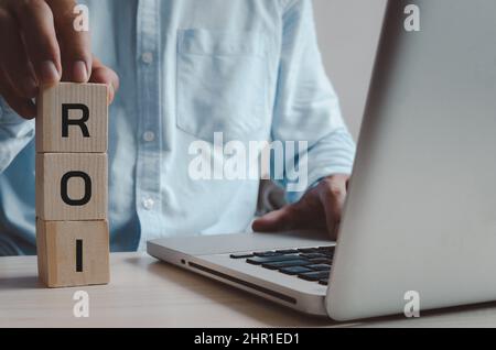 Cubi di legno con ROI Return on Investment Symbol sulla scrivania con computer e copy space.Business concetti. Foto Stock