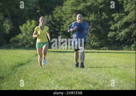 coppia jogging insieme attraverso un prato, vista frontale Foto Stock