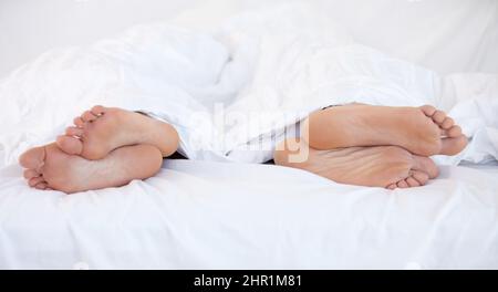 Crescere a parte.... Immagine ritagliata dei piedi di due persone a letto che si affacciano in due direzioni diverse. Foto Stock