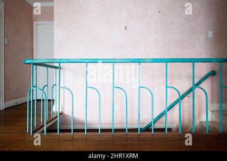 Una ringhiera in legno staicase con mandrini decorativi in metallo dipinti turchesi in una casa di metà secolo. Questa casa è stata demolita. Foto Stock