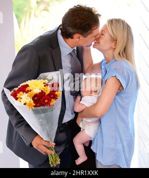 Questi sono per voi, belli. Giovane padre che porta a casa fiori alla sua bella famiglia. Foto Stock