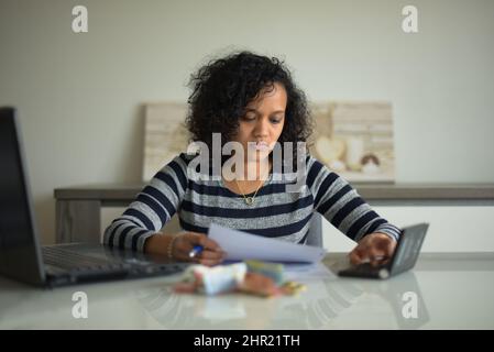 metis donna che controlla le sue fatture a casa Foto Stock