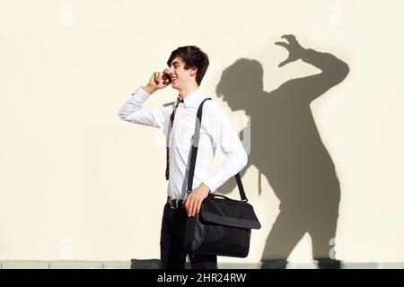 Le sue paure non sono mai lontane dietro di lui. Colpo di un giovane che è stato colpito da una oscura ombra di se stesso. Foto Stock