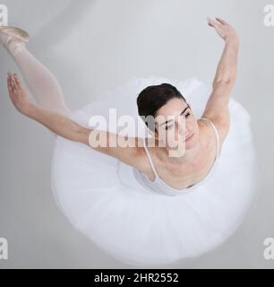 Pieno di eleganza e grazia. Ballerina giovane e flessibile su sfondo bianco. Foto Stock