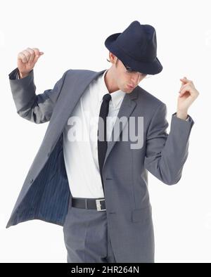 Con uno scatto e un shuffle. Un giovane uomo in abito e cappello che balla su sfondo bianco. Foto Stock