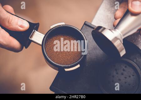 Barista manomissione caffè in portafiltro con manomissione. Primo piano del processo di preparazione del caffè fresco Foto Stock