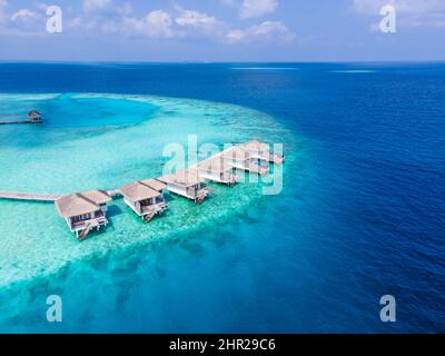 Ville sull'acqua sull'isola tropicale dell'atollo per vacanze di viaggio e luna di miele. Hotel resort di lusso nelle Maldive o nei Caraibi con mare turchese Foto Stock