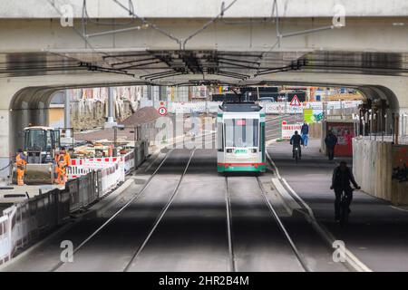 Magdeburg, Germania. 24th Feb 2022. I ciclisti e un tram attraversano una parte già rilasciata del cantiere del City Tunnel. I lavori di costruzione sono iniziati nel 2015 e sono attualmente in corso lavori sul fondo stradale nelle gallerie d'auto. Il completamento e la consegna del progetto sono previsti nel dicembre 2022. Credit: Klaus-Dietmar Gabbert/dpa-Zentralbild/ZB/dpa/Alamy Live News Foto Stock