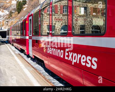 ALP Grum, Svizzera - 19 gennaio 2022: Treno panoramico turistico rosso Bernina Express che corre tra Chur e Tirano in Italia e attraversa Bernina mou Foto Stock