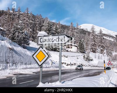 Cinuos-Chel, Svizzera - 3 febbraio 2022: Il paesaggio invernale nevoso dell'Engadina e un cartello con il nome del villaggio di Cinuos Chel a Griso Foto Stock